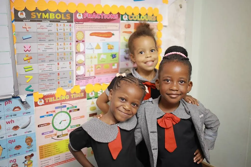 Three smiling pupils together in a colourful classroom