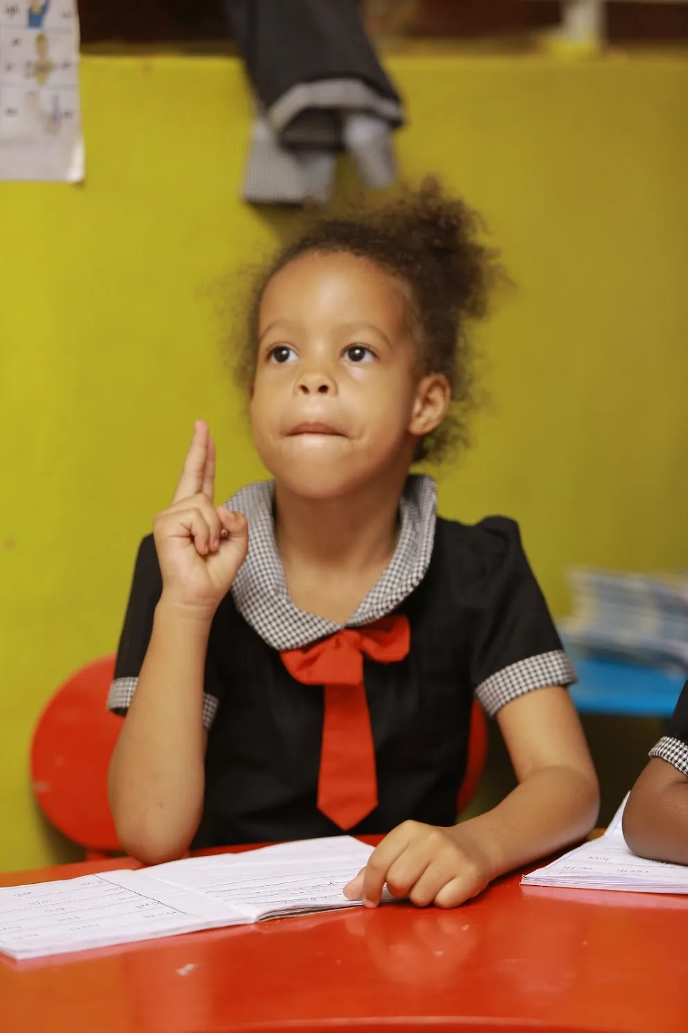 A pupil raising her hand eagerly during a lesson